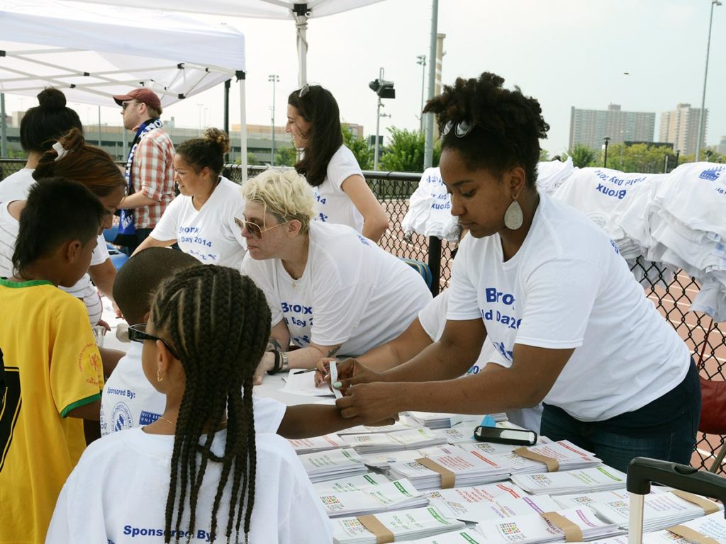 Сотрудники LAS раздают значки и помогают членам сообщества за столом для регистрации в день поля.